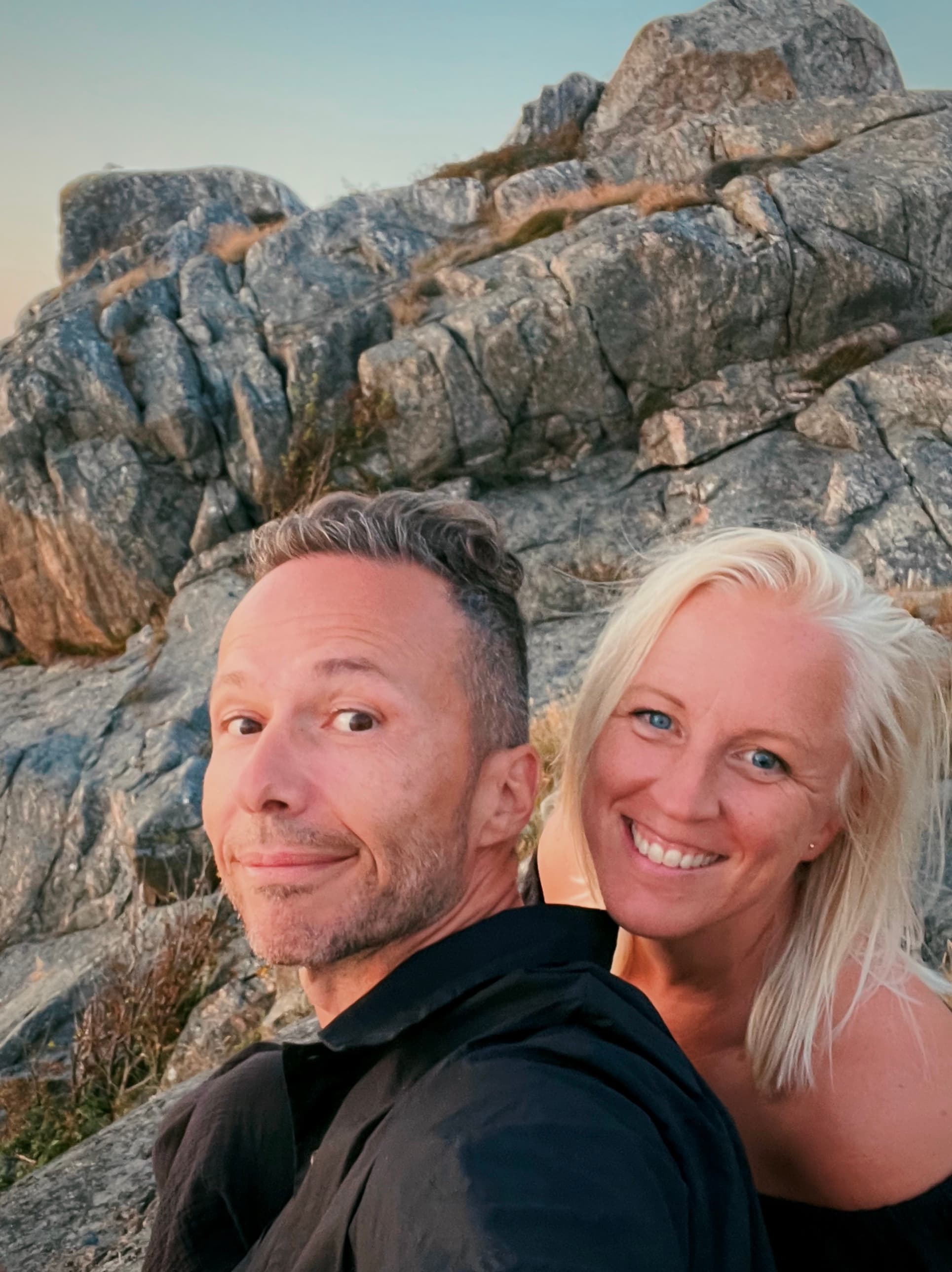 Panos and Emma smiling together in front of a rocky hillside